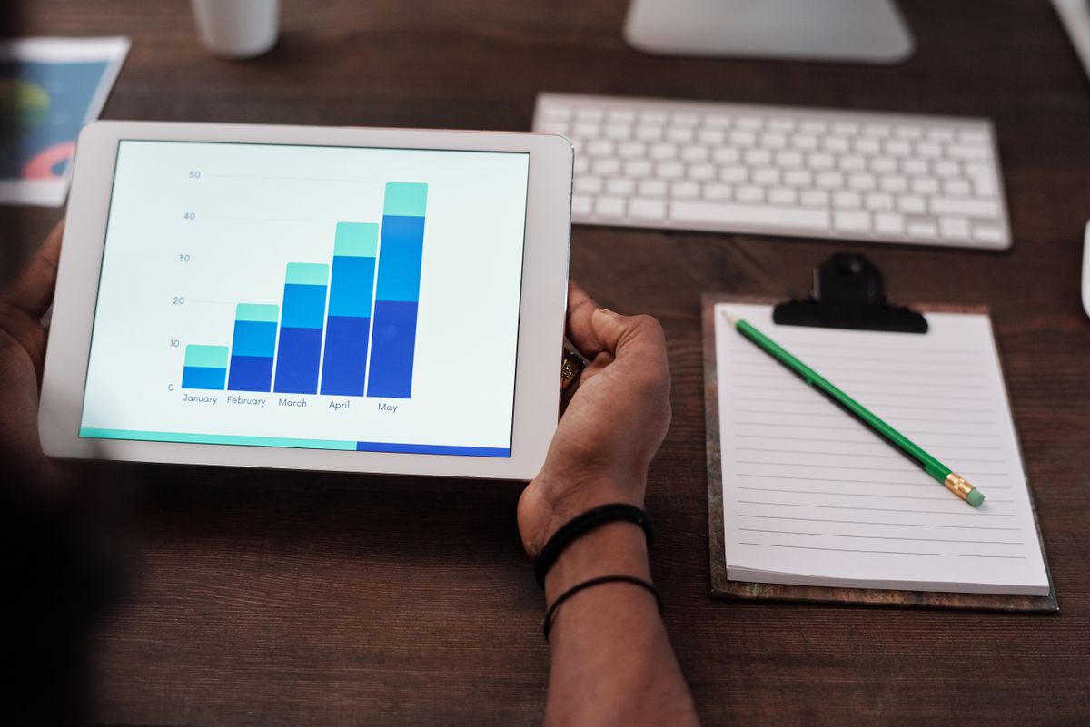 Tablet showing an automated bar chart report beside a notepad