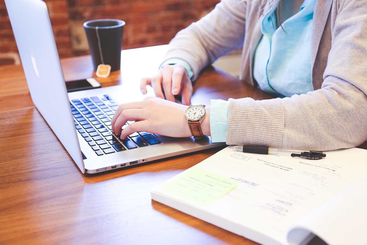 Business owner typing on a laptop next to handwritten notes