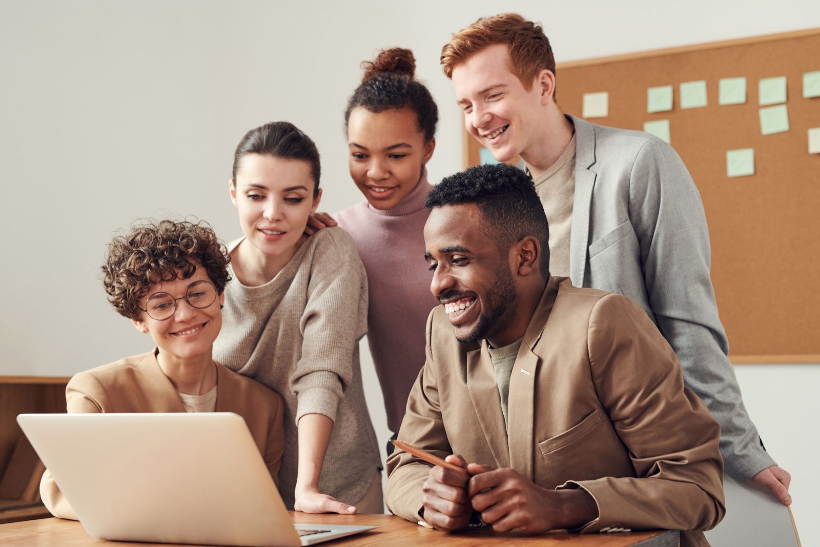 Smiling team gathered around a laptop reviewing project progress